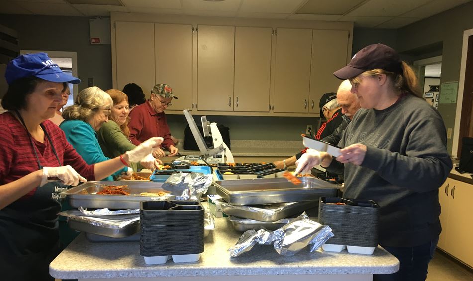 People in a kitchen making meals for seniors